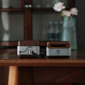 Cute Doggy AirPods Pro Case Wood Walnut Leather iwoodstore Two wooden and metal items on a wooden surface with a blurred background