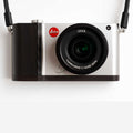Silver Leica TL2 camera with attached dark ebony ergonomic handgrip, front view.
