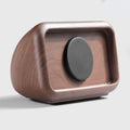 Wooden square object with a central black circular component on a light gray background