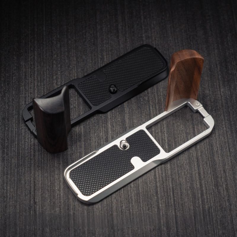YW Design Handcrafted Wooden Grip for OM-System PEN A close-up of a knife or tool handle replacement set on a dark wood-textured background, showing a black textured handle grip with a dark wood handle section and a silver metal guard with a black grip insert.