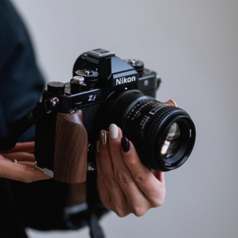 Person holding a Nikon ZF camera against a plain background