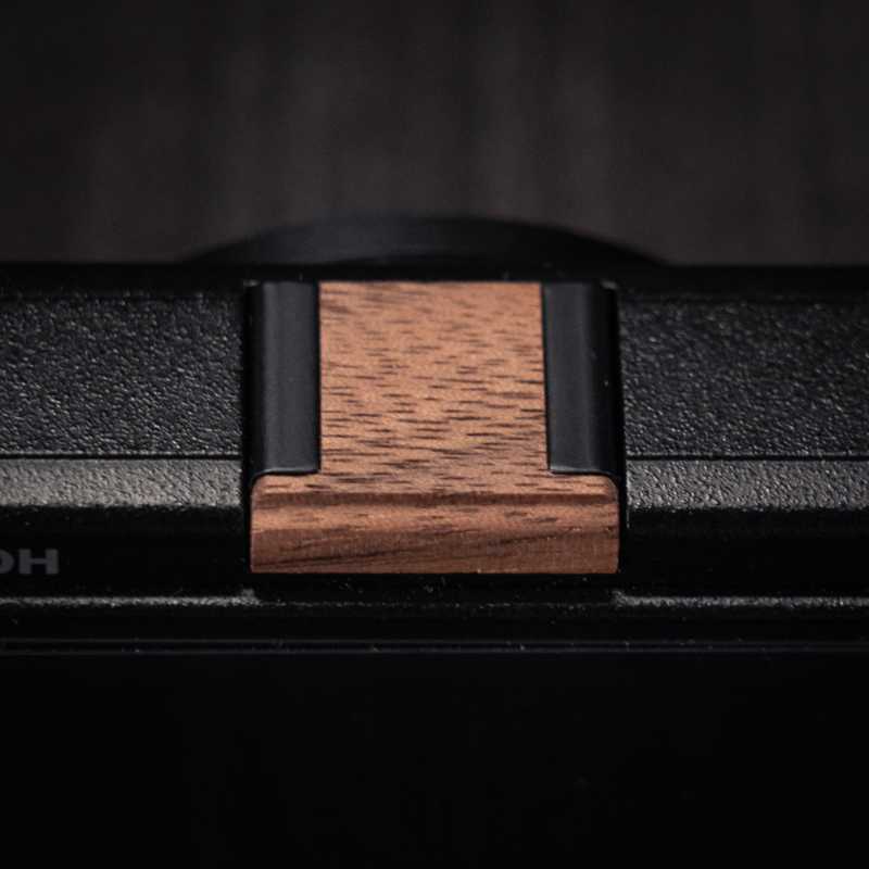 Ricoh GR4 Hotshoe Cover Wood iWoodStore Close-up of a wooden belt buckle on a black belt with a dark background