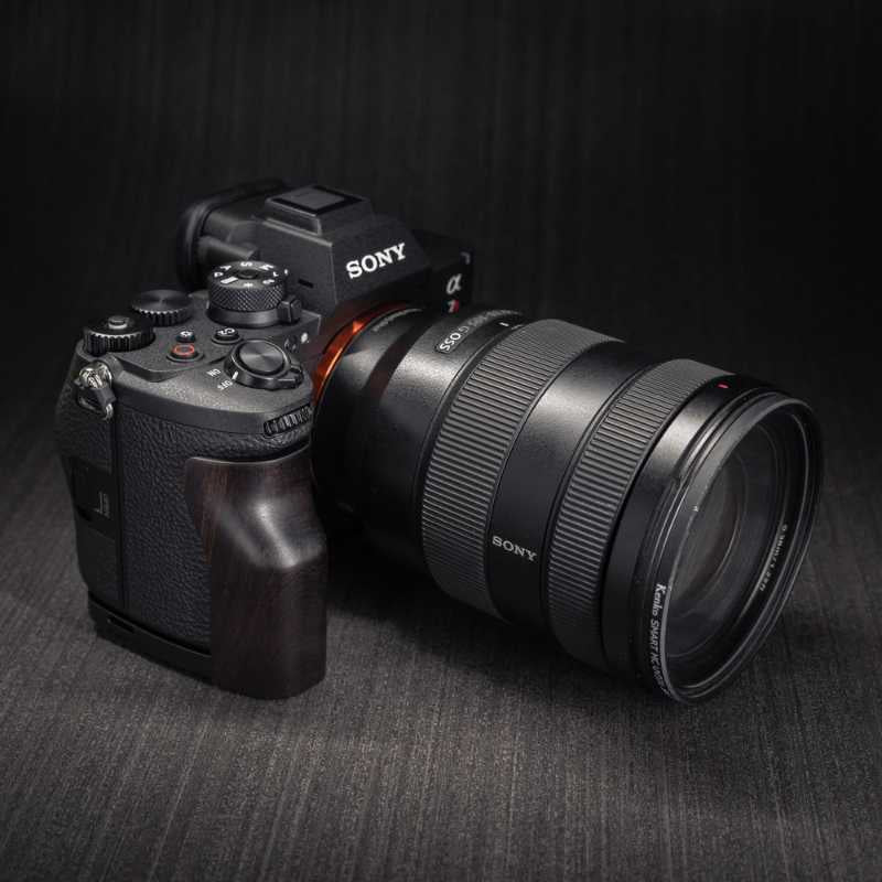 Sony Alpha 7R mirrorless camera body with an attached battery grip and a black lens protector cap, shown on a clean white background.