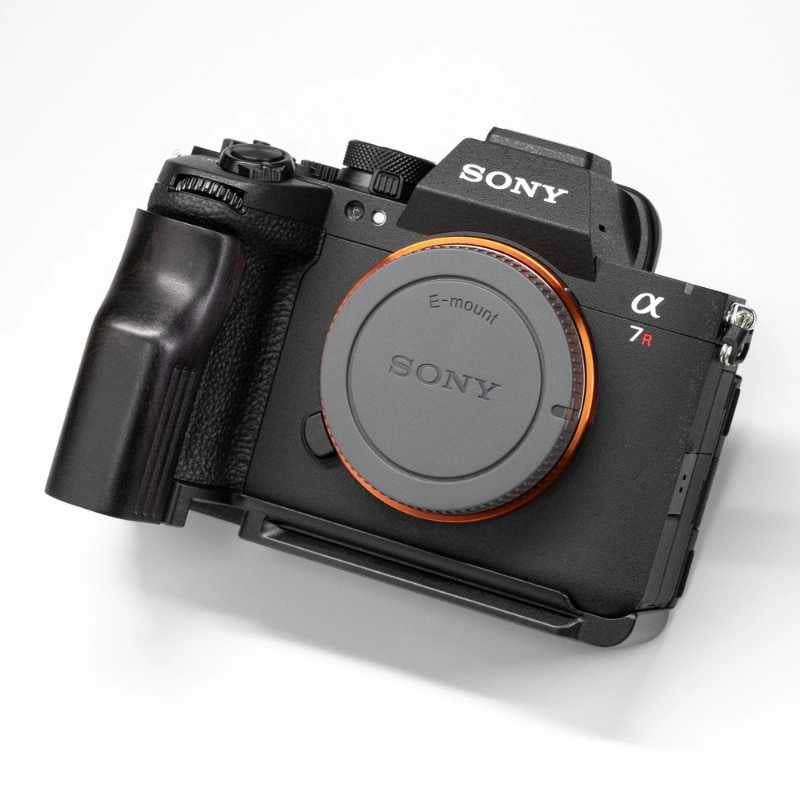 Sony Alpha 7R mirrorless camera body with an attached battery grip and a black lens protector cap, shown on a clean white background.