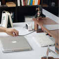 Wood Telescopic Retractable Data Cable Charging Cable For Desk iWoodStore Person plugging a cable into a laptop on a desk with a keyboard and other items.