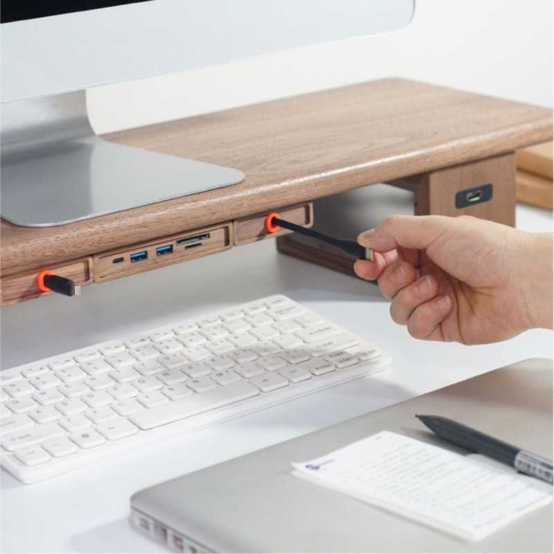 Wood Telescopic Retractable Data Cable Charging Cable For Desk iWoodStore Hand plugging a pen into a USB hub attached to a desk with a computer setup.